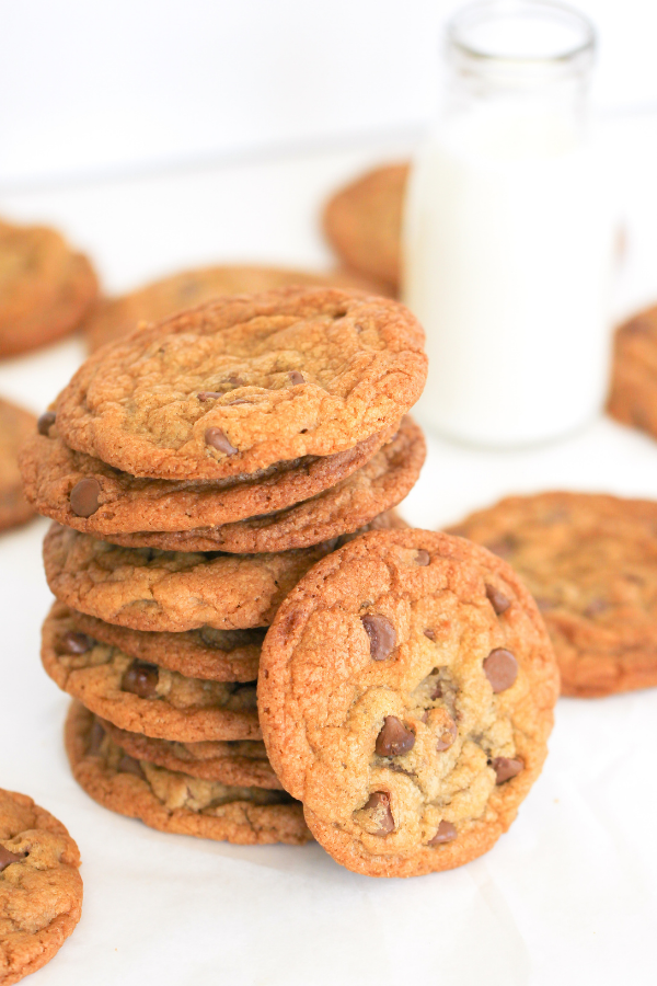 A stack of chocolate chip cookies with a small bottle of milk in the background